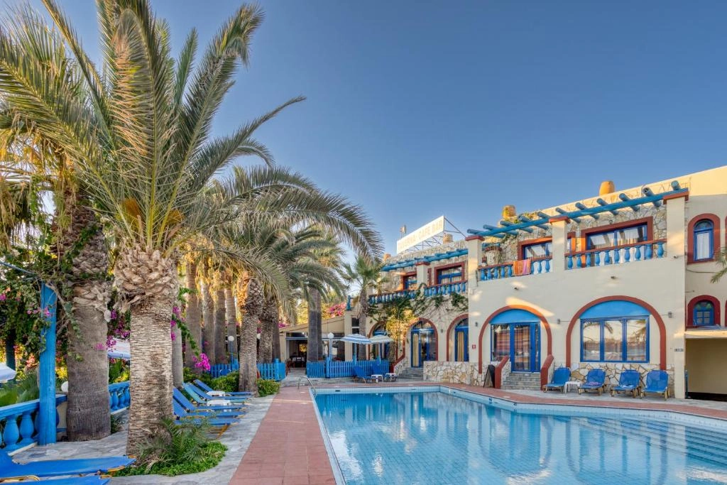Πισίνα Palm Bay Sissi Hotel στο ηλιοβασίλεμα με φοίνικες και μπουκαμβίλιες